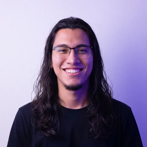 The same man as a studio headshot in a black tee against a lilac backdrop