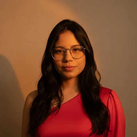 The same woman as a studio headshot lit warmly against a plain wall