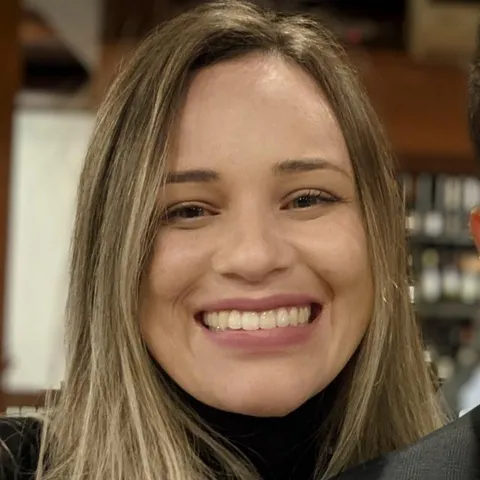Casual phone selfie of a smiling woman in a black turtleneck at a restaurant